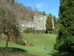 a sloping lawn in front of a castellated mansion