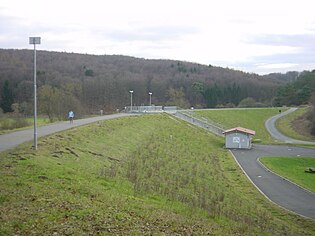 Staudamm mit mittigem Auslassbauwerk und Betriebsgebäude; Blick vom Nordende des Damms nach Süden