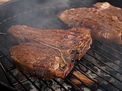 A T-bone steak being cooked on a grill