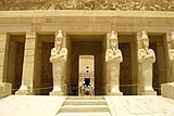 Tall stone statues of Hatshepsut with crossed arms holding a sceptre and a flagellum