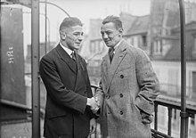 Photographie en noir et blanc de deux hommes en costume se serrant la main.