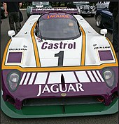 Photographie d'un voiture de sport-prototypes blanche et violette, arrêtée, vue de face.