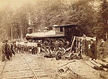 A crowd of people viewing a derailed steam locomotive