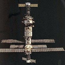 A spacecraft docked to the Mir space station, in front of a dark space background