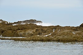 Waves crashing through the limestone rocks during stormy weather.