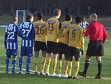 Six players standing in a line, being talked to by another man.
