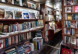 Inside of the Word on the Water's canal boat. Books sprawl across dark wooden shelves.