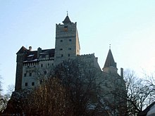 Vue en contre-plongée d'un château moyenâgeux avec son donjon au centre.