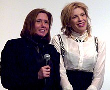 Two women facing an audience, holding microphones