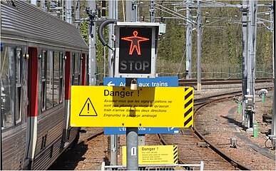 Signalisation lumineuse disposée à l'extrémité du quai lorsque la sortie des voyageurs est incompatible avec la fermeture du passage à niveau.