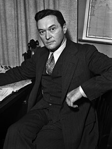 Lippmann wearing a suit, sitting a desk, facing the camera