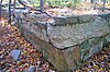 An angular stone retaining wall with dead leaves in a forest