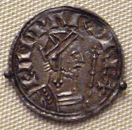 A coin depicting a bearded man facing to the right holding a sceptre, with a Latin inscription going from left to right over him