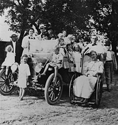 A Johnson Family gathering in 1912. The third adult from left in the back row is Sam Ealy Johnson Jr. His wife, Rebekah Baines Johnson, is in front of him. Sam Ealy Johnson Jr.'s mother, Eliza Bunton Johnson, is seated in the wheelchair. Lyndon B. Johnson (four years old) is standing in front of the automobile.