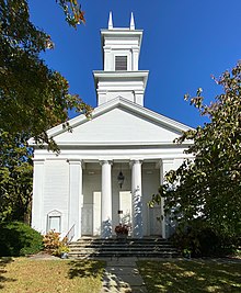 Full view of a white church, including main entrance and steeple