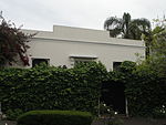 Free-standing single storey vernacular cottage; stepped parapet wall with plaster mouldings and full hipped corrugated iron roof behind; sash windows (12 panes); unpainted timber window frames and shutters; unpainted panelled door with fanlight and small Type of site: House Current use: House.