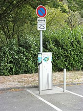 Photographie en couleurs d'une borne sur un parking.