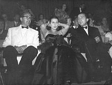 Deux hommes et une femme assis avec un large public derrière - on reconnaît à gauche Giulio Andreotti et Anna Magnani
