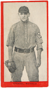 a young man in an old-style baseball uniform wears a glove and stares at the camera