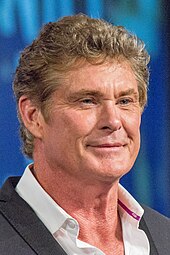 An image of Hasselhoff in a white collared shirt and black suit
