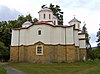 Back view of a white monastery church with an apse featuring a sharp-pointed window bay and four domes visible