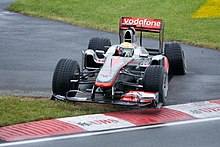Lewis Hamilton driving a McLaren Formula One car with a damaged left rear tyre