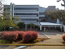 A four-story glass-and-steel office building with large ventillation shafts on the outside