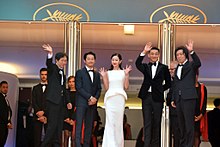 A cast, including Yeun smiling and waving