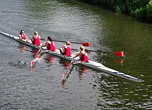 Four rowers and a cox in red rowing on a river