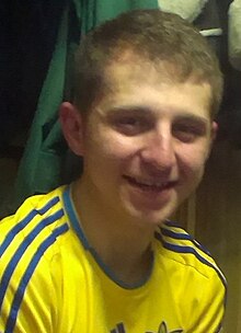 Ihor Kostenko in 2013 wearing a yellow Ukrainian sports jersey. He is a young man with blond hair smiling at the camera.