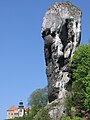 The Cudgel of Hercules, a tall limestone rock formation, with Pieskowa Skała Castle in the background