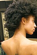 A woman with kinky hair: her hair has tight coils.