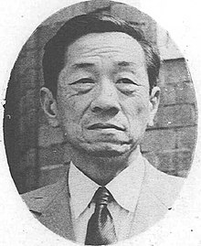 Asian man facing front, in suit and tie.