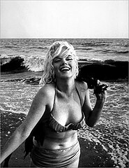 Monroe on a beach, wearing a bikini and laughing.