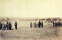 Photograph showing a line of artillery batteries standing at the ready in the foreground with cavalry and other troops massed in the background