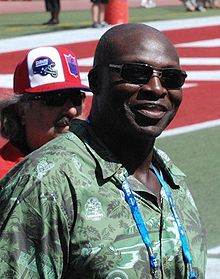 Bruce Smith smiling with sun glasses and a green shirt on.