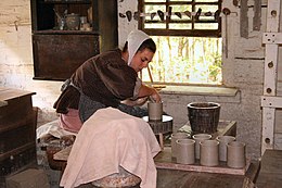 Young woman in period clothing at a pottery wheel