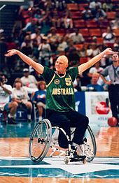 Joueur en fauteuil qui lève les bras en l'air pour faire réagir les spectateurs.