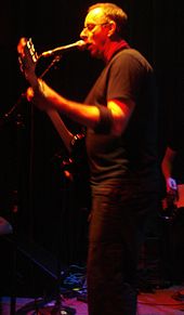 A man performing live onstage with an electric guitar.