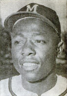 A man in a light baseball uniform and a dark cap with an "M" on the center