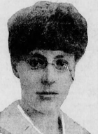 Headshot of a woman wearing a fur hat and eyeglasses