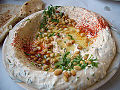 A plate of hummus, garnished with paprika and olive oil and pine nuts