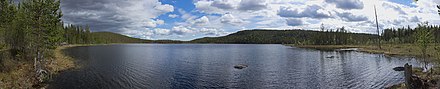 Lac entouré de collines couvertes de forêts de conifères.