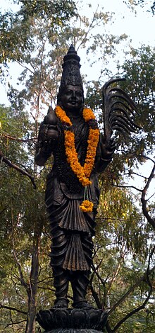 Black outdoor statue with an orange garland