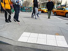 Photograph of white bump tiling in a curb cut