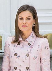 Photographie d'une femme aux cheveux châtains portant une veste rose à fleurs.