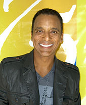 Jon Secada smiling, facing front.