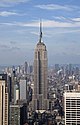 Aerial view of a 100-story building with several setbacks; the building tapers into a large circular spire near its 90th floor and is topped by a large antenna.