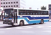 西鉄が1980年代に導入した車両は写真のような「青特急色」と呼ばれる白地に青色濃淡帯・金色細帯の塗装であった。この塗装は当時の他の西鉄の短距離高速バス路線でも使用されていた。写真の高塚発着便は現在は廃止された。