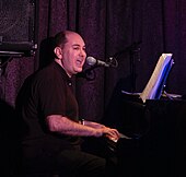 A man playing a piano, and singing